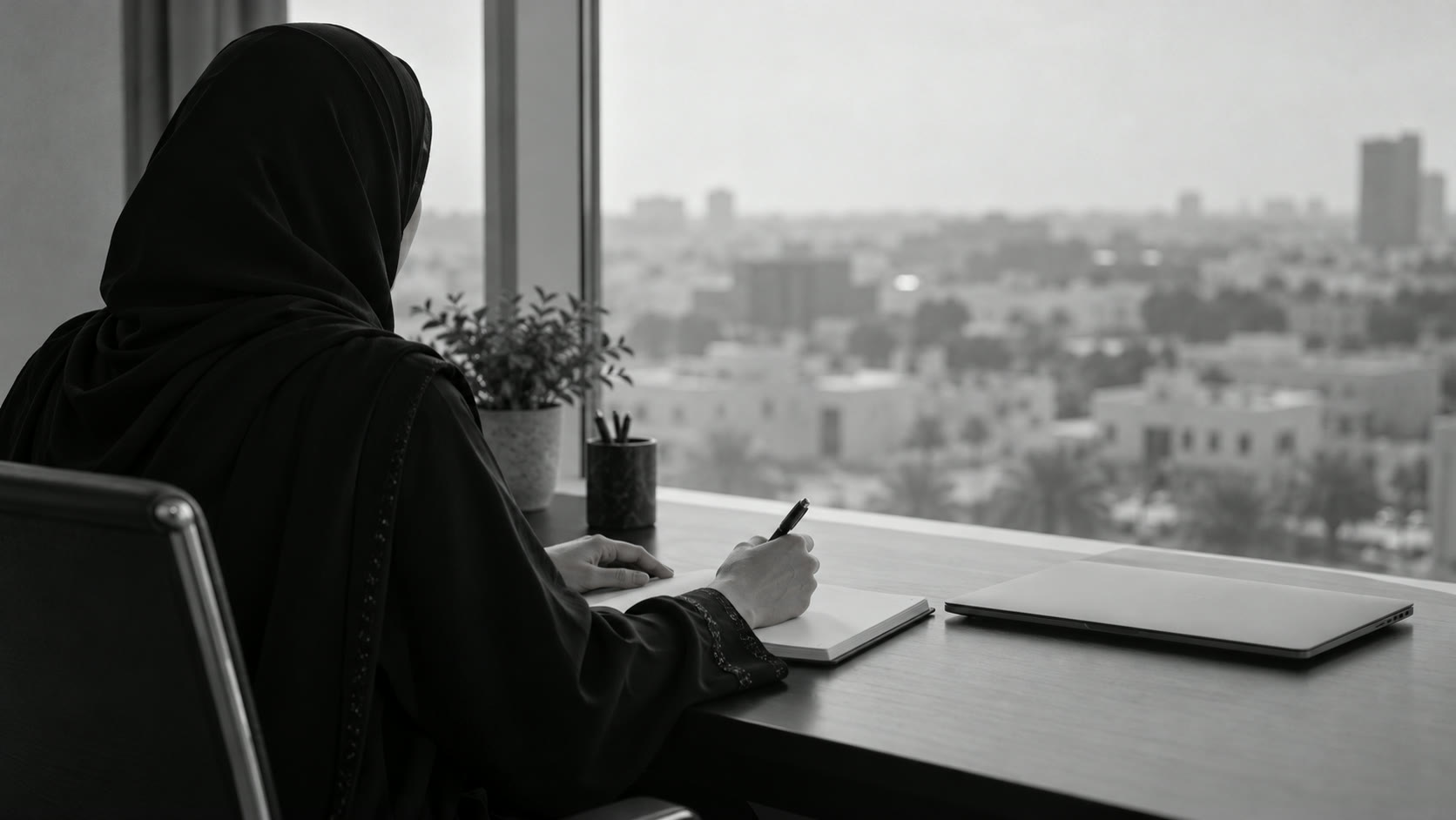 A professional working at a desk by a window over Riyadh